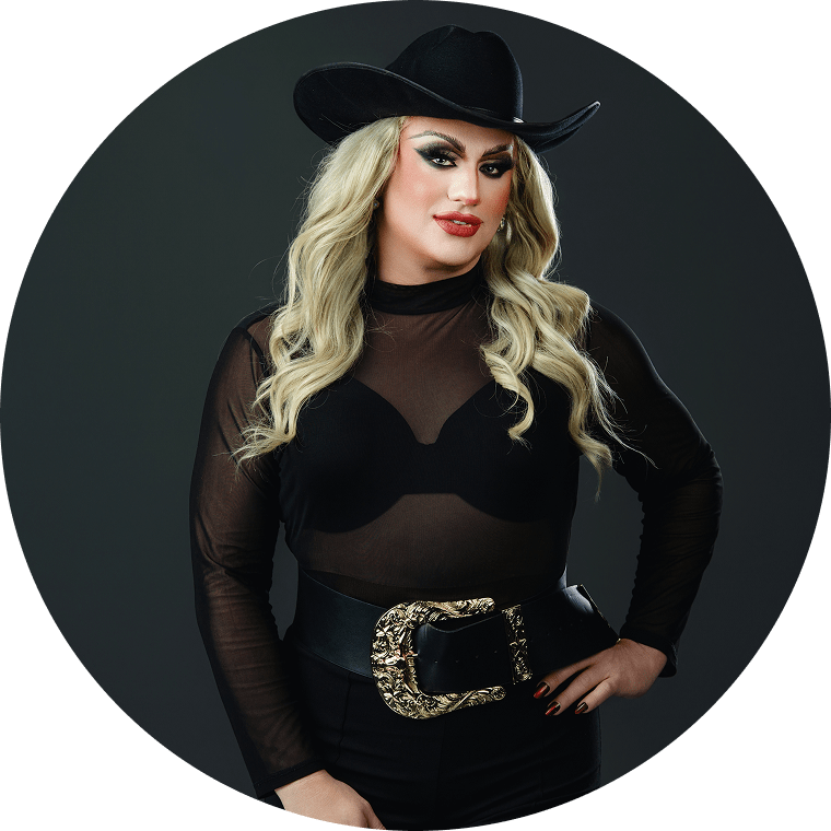 tracey the drag queen wears a blonde wig, black cowboy hat, black outfit, and a gold belt buckle