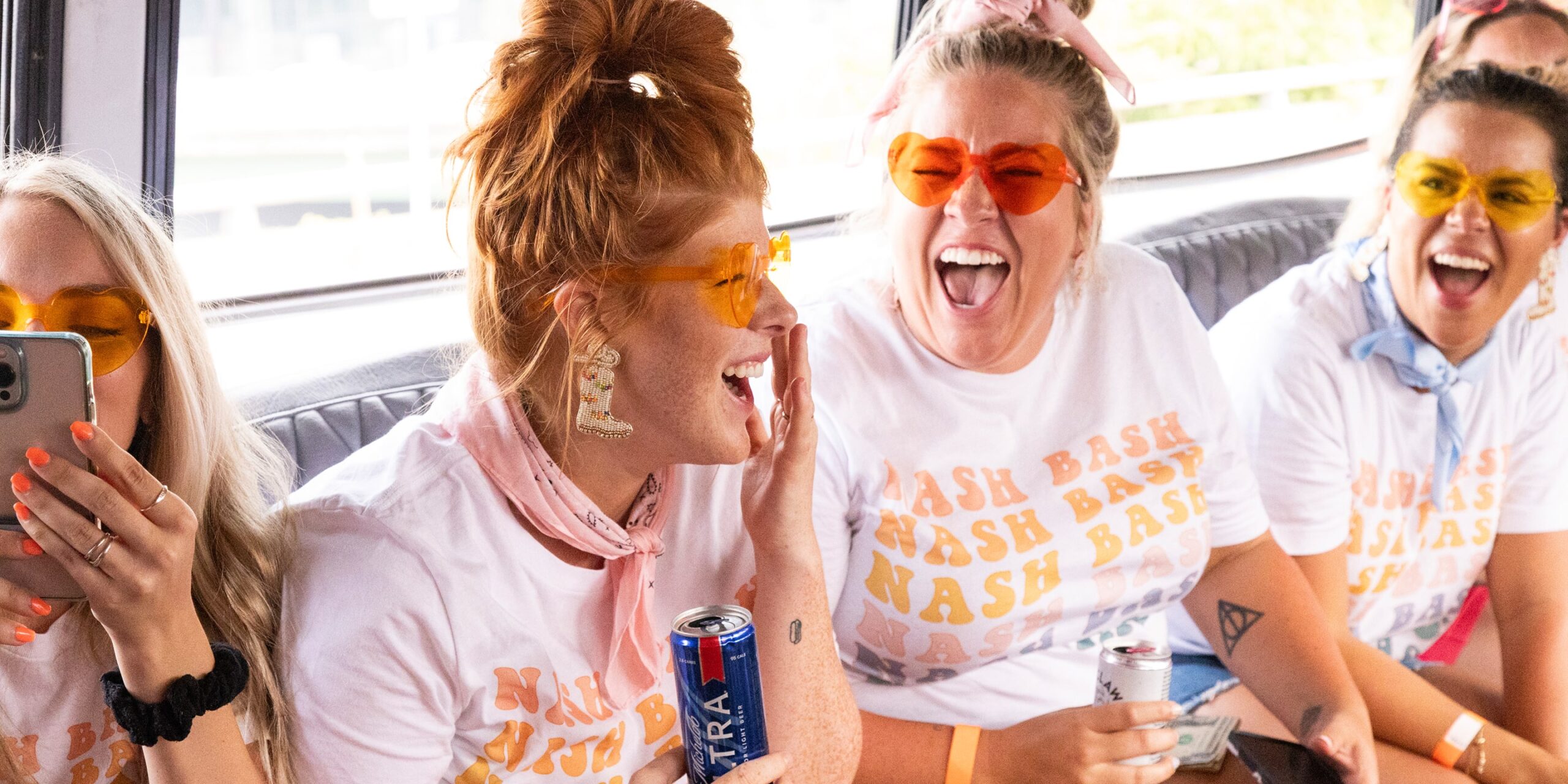 four women on a bachelorette party in nashville laugh and smile in matching tshirts and sunglasses