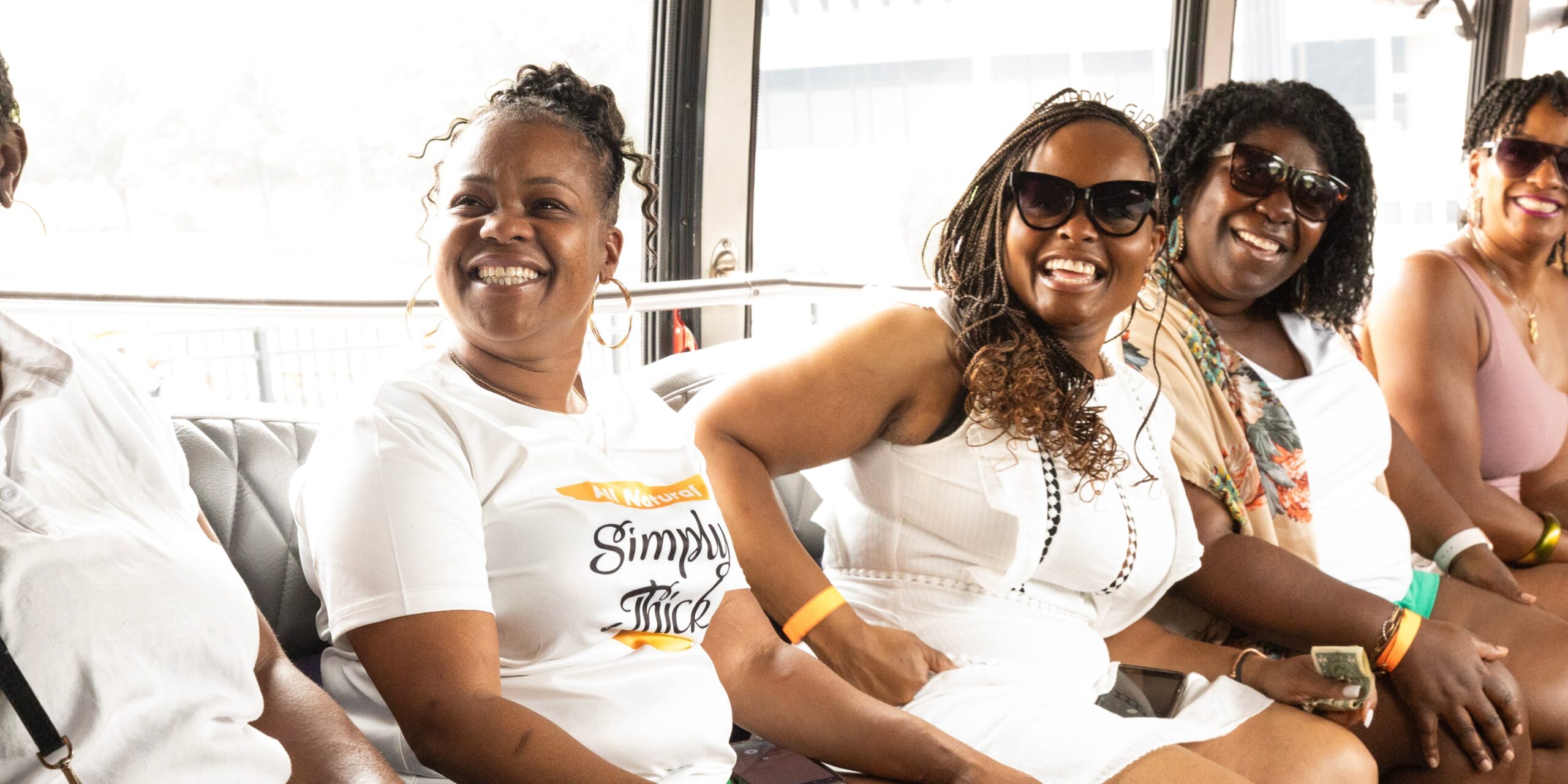 three women smile and laugh on a party bus tour in nashville
