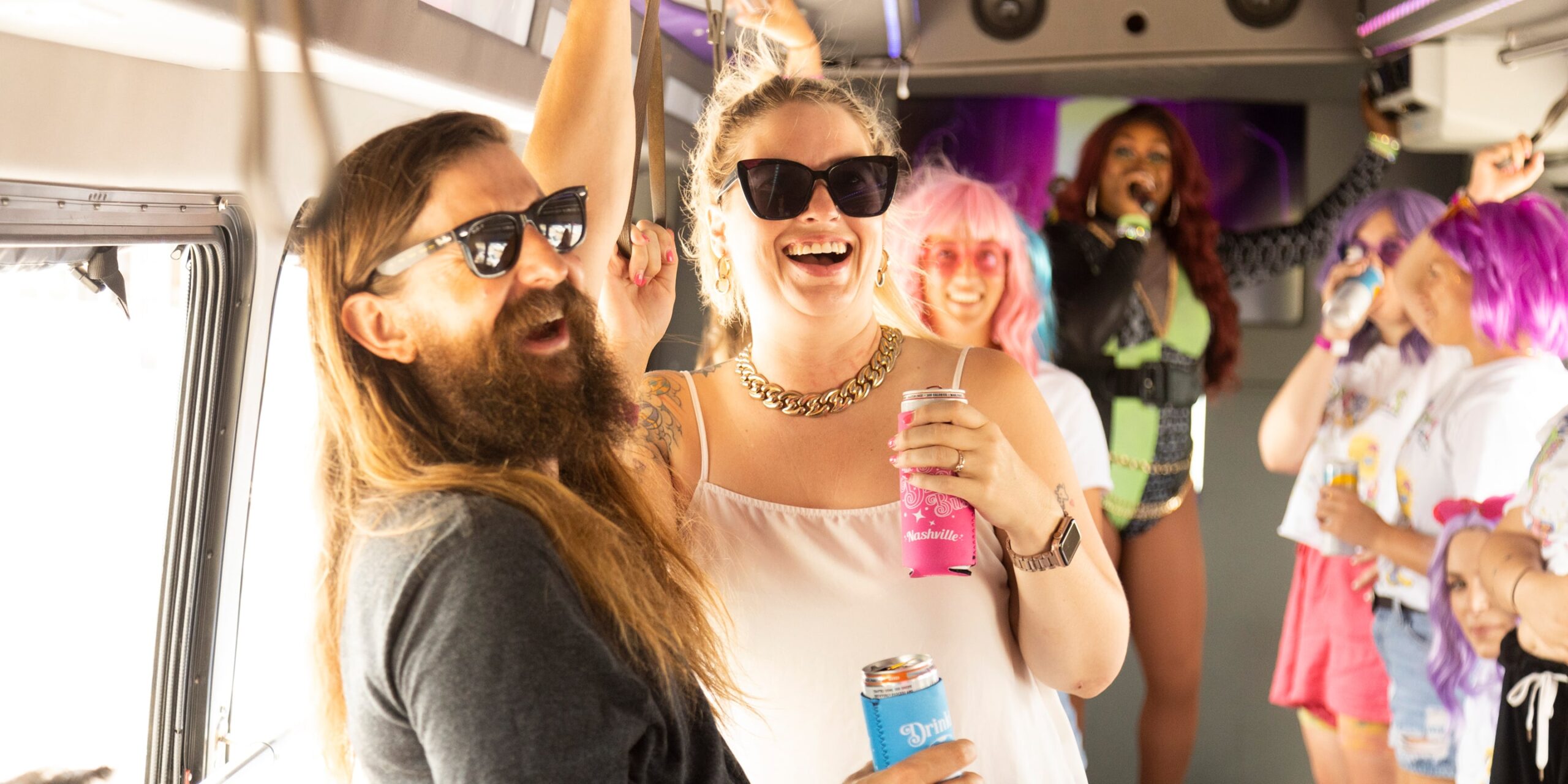 a white man with a beard and a white woman smile and dance with a drag queen behind them