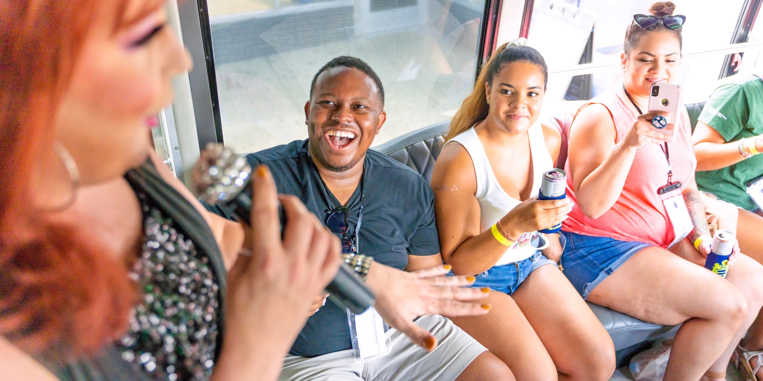 a group of people smile and take photos of a drag queen on a party bus
