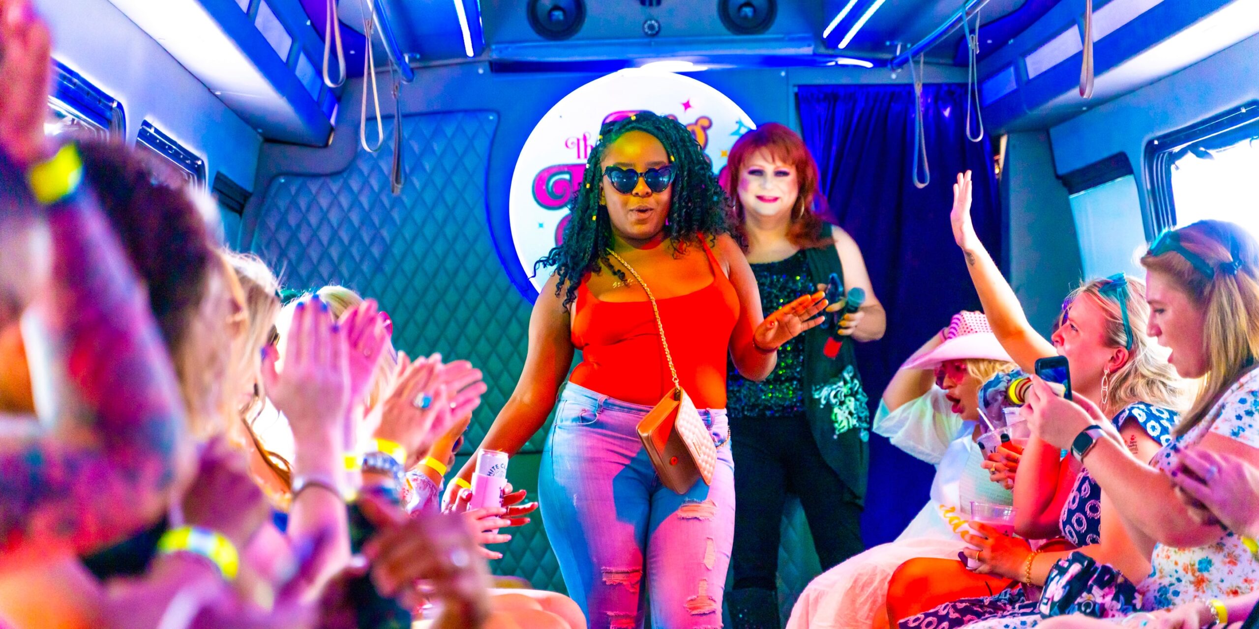 a black woman in a red tank top and sunglasses dances down the nashville drag bus runway